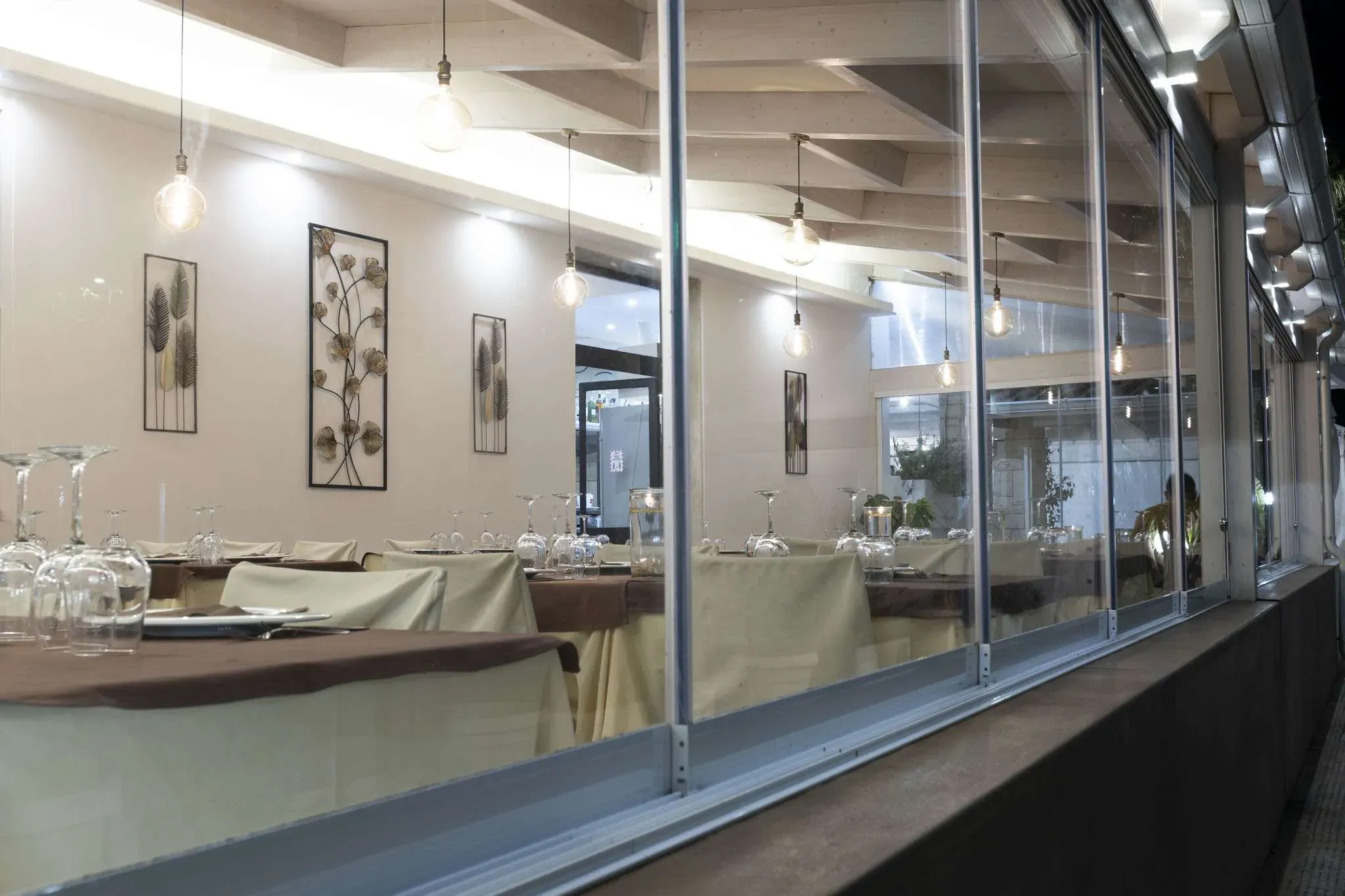 La sala interna di Porto Adriano con tavoli apparecchiati e ampie vetrate